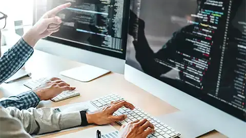 Hands working on a computer. Source code on screen.
