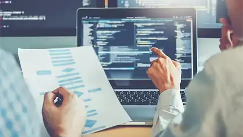 Hands working on a computer. Source code on screen.